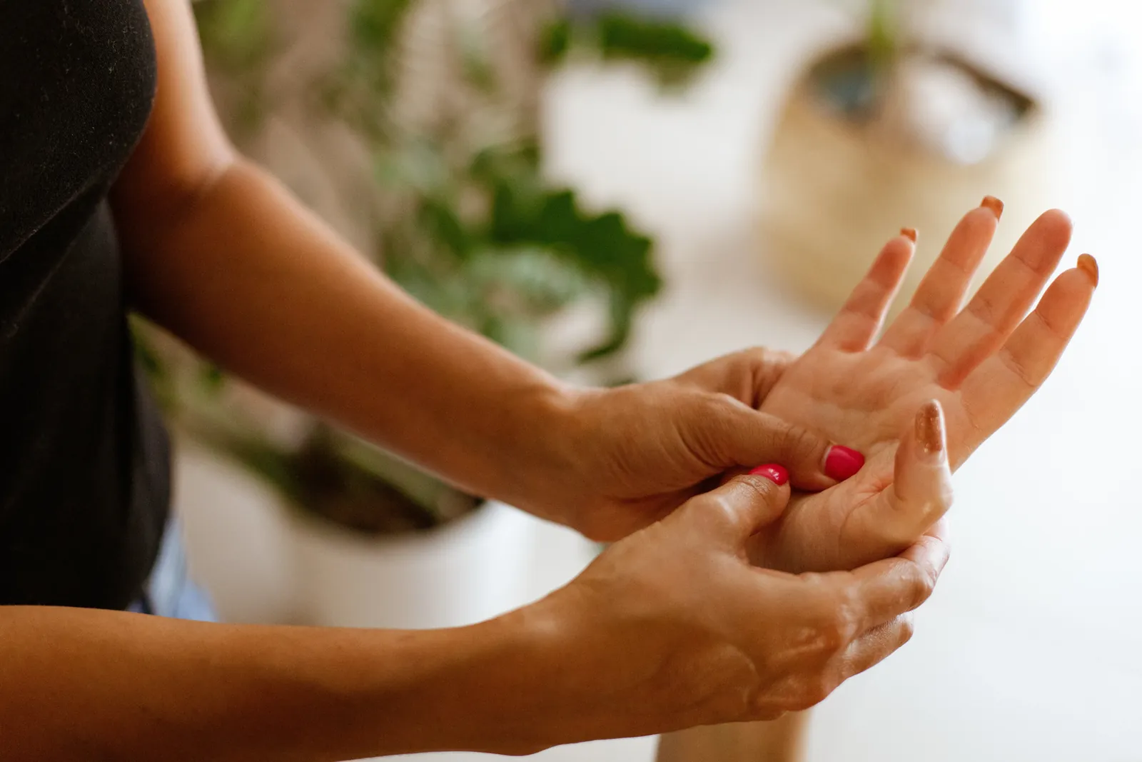 Les mains d'une praticienne massent la paume d'une main