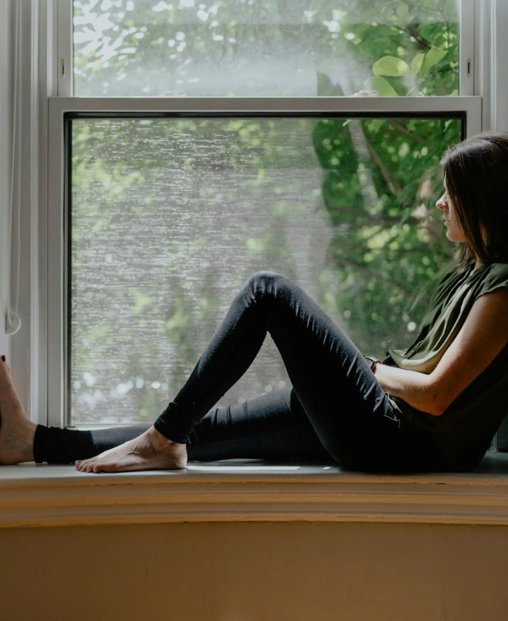 Femme assise près d'une fenêtre, lumière naturelle